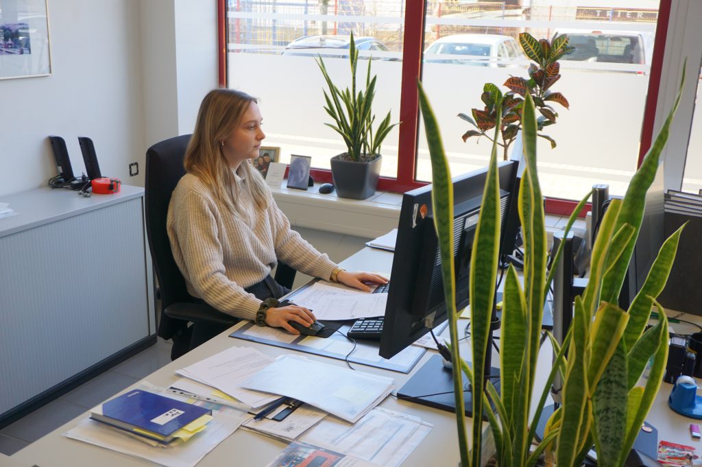 Mitarbeiterin von sbt Trier bearbeitet Unterlagen am PC im Büro