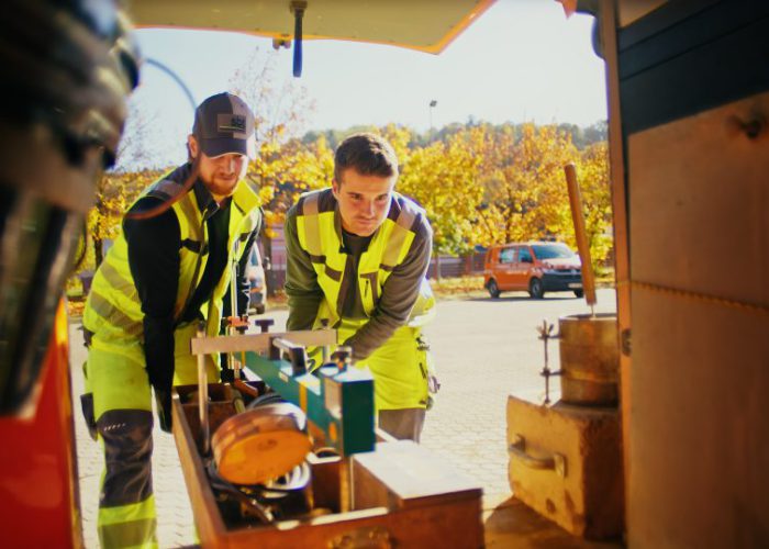 Zwei Mitarbeiter von sbt Trier prüfen ein Messgerät am Außendienstfahrzeug