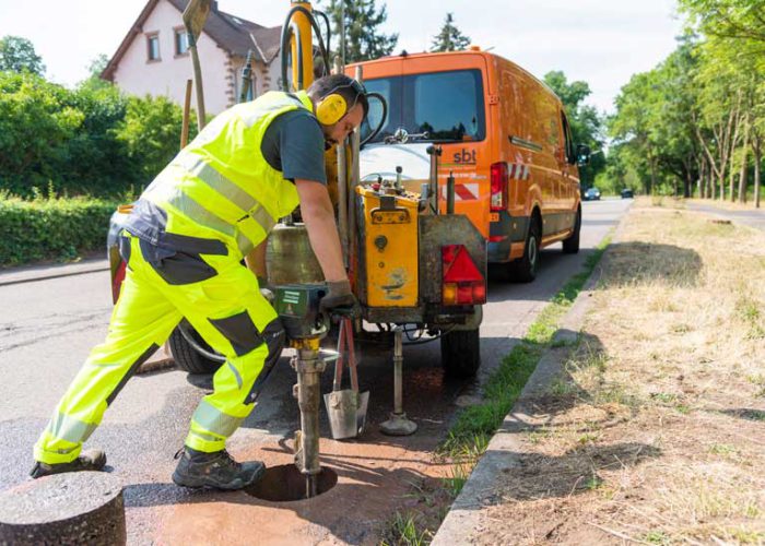 Mitarbeiter von sbt Trier führt Asphaltbohrung an einer Straße durch